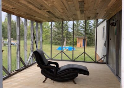 A lounge chair in a beautifully refinished cedar board ceiling sunroom.