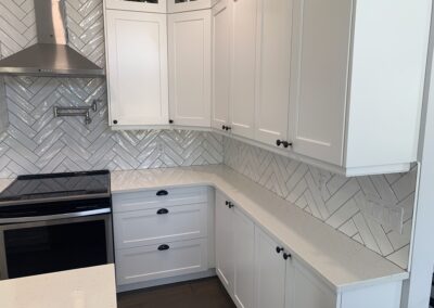 A kitchen renovation with beautiful white gloss tile backsplash.