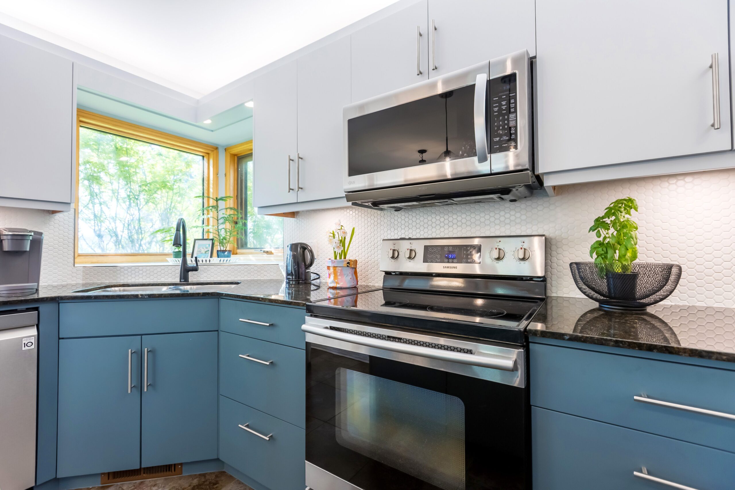 An image with a beautiful kitchen renovation with grey upper cabinet and blue lower cabinets, beautiful white backsplash.